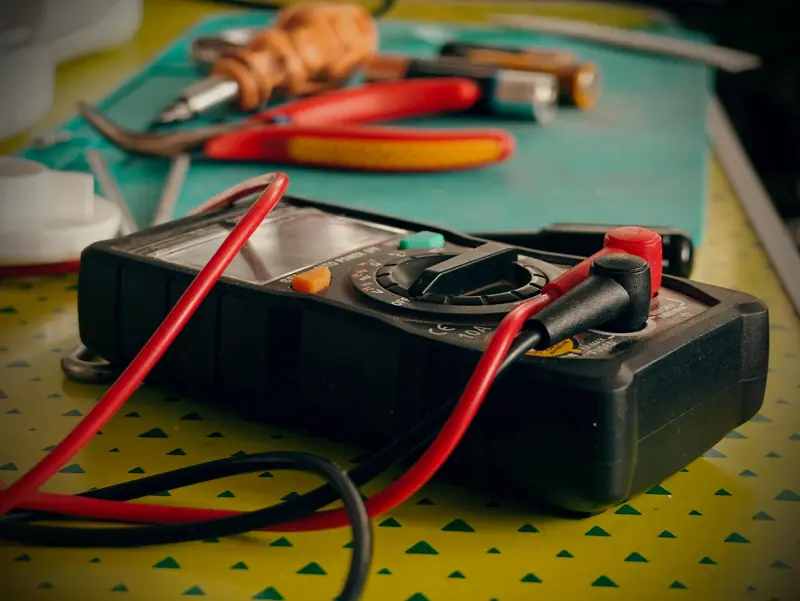 Multímetro con pinzas y herramientas de electricista sobre una mesa — electricista matriculado en Berazategui